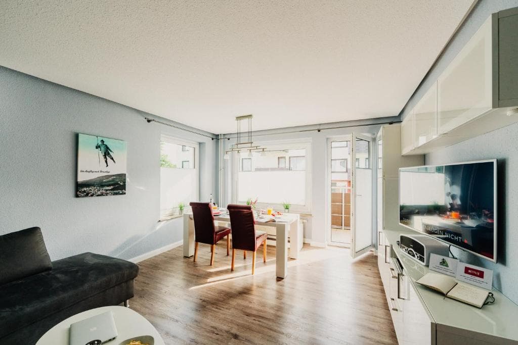 Wohnbereich mit Sofa, Essplatz und Tür zum Balkon